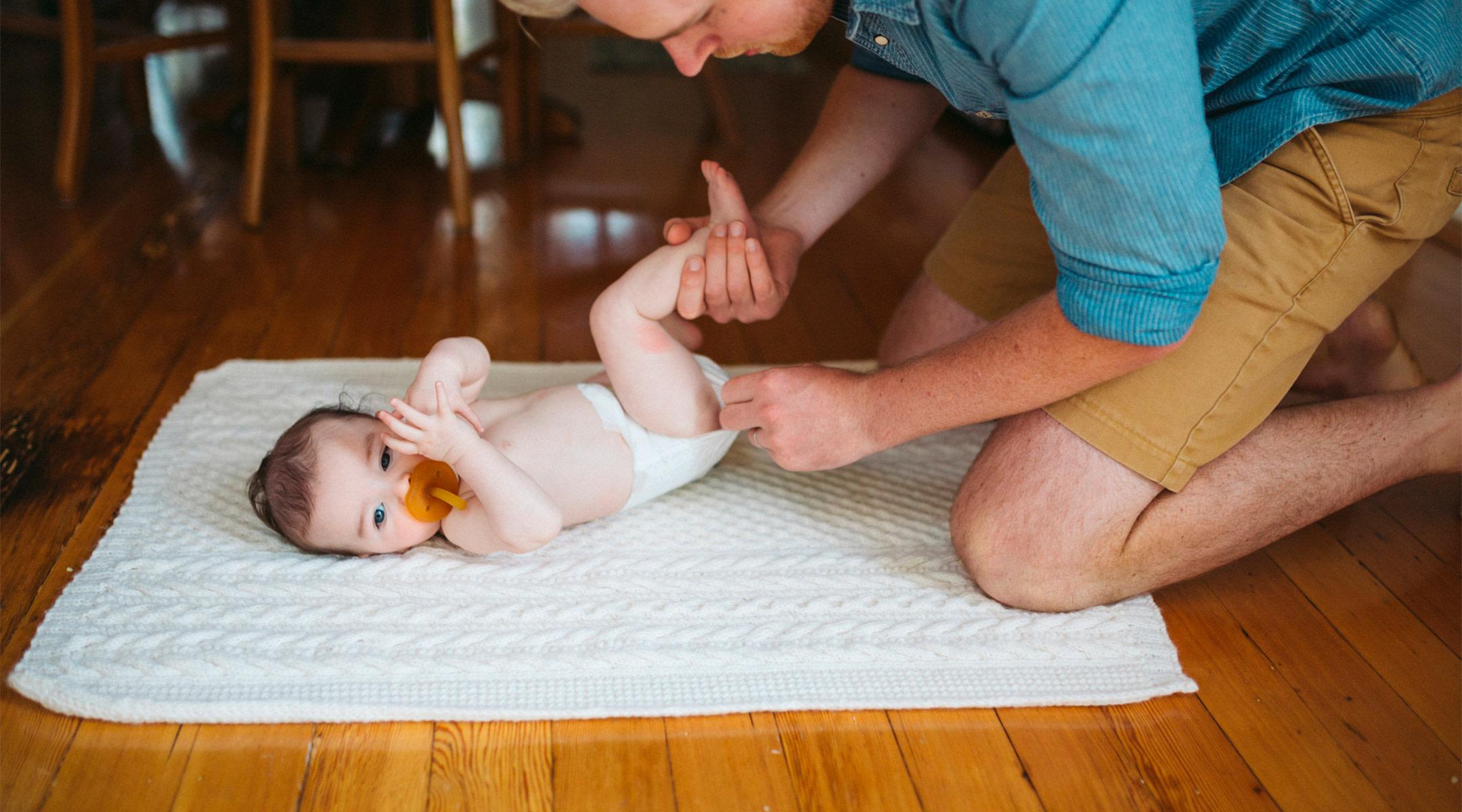 dad changing baby's diaper on the floor