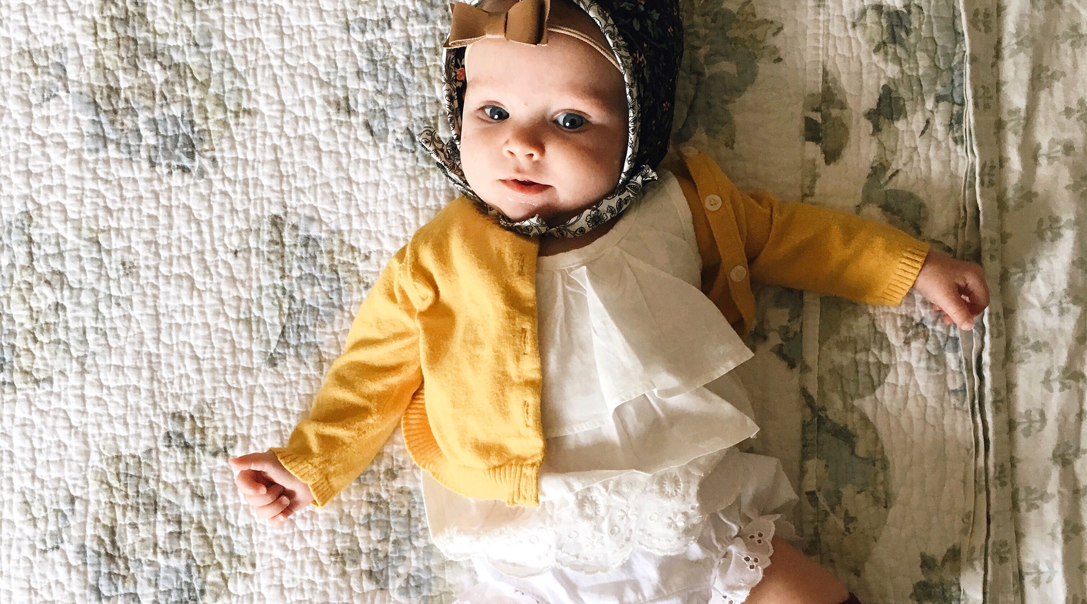 baby dressed in pretty bonnet, with gold bow and cute socks