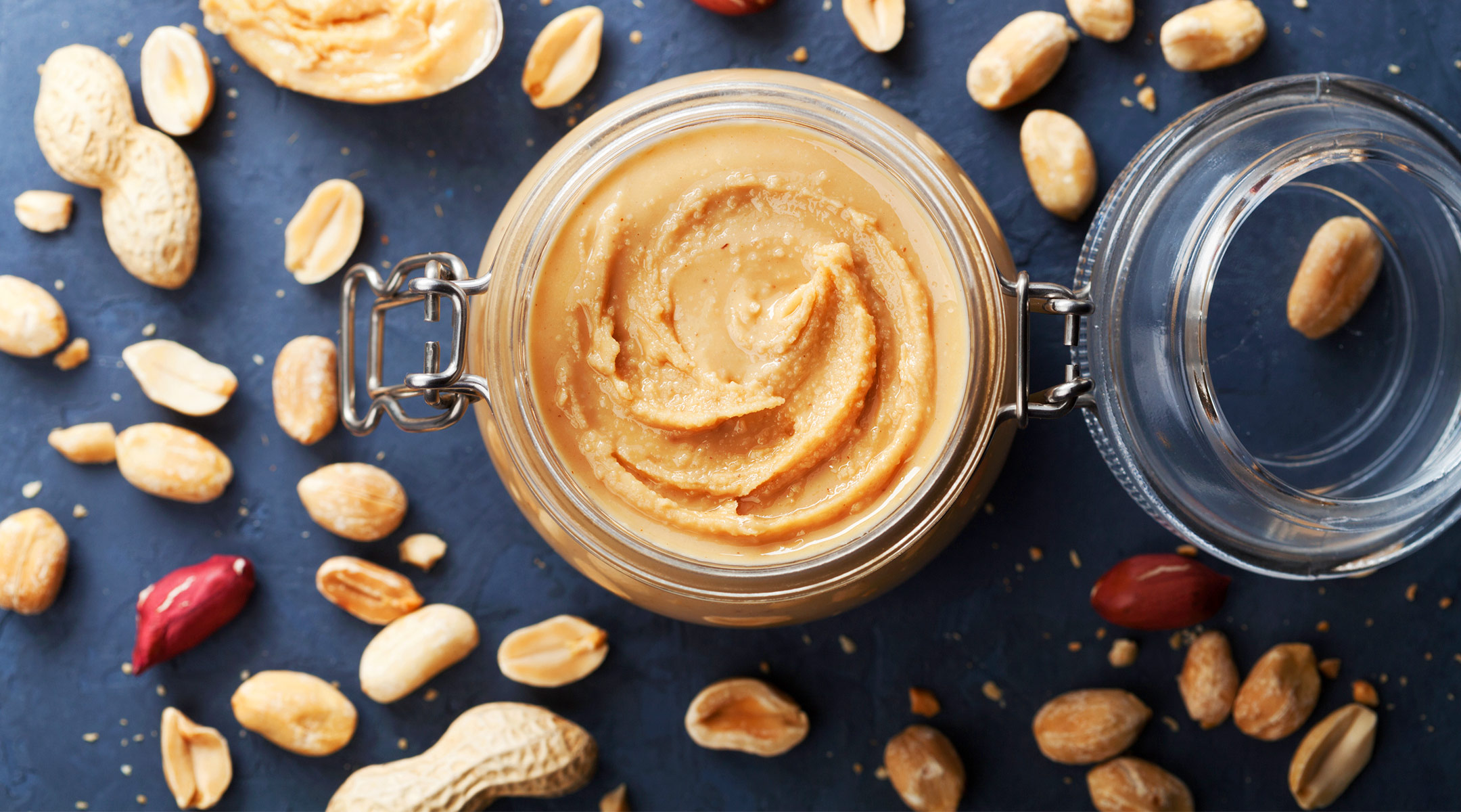 peanut butter in a jar surrounded by peanuts