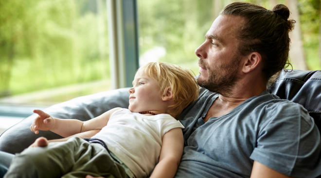 dad holding young son looks out of window