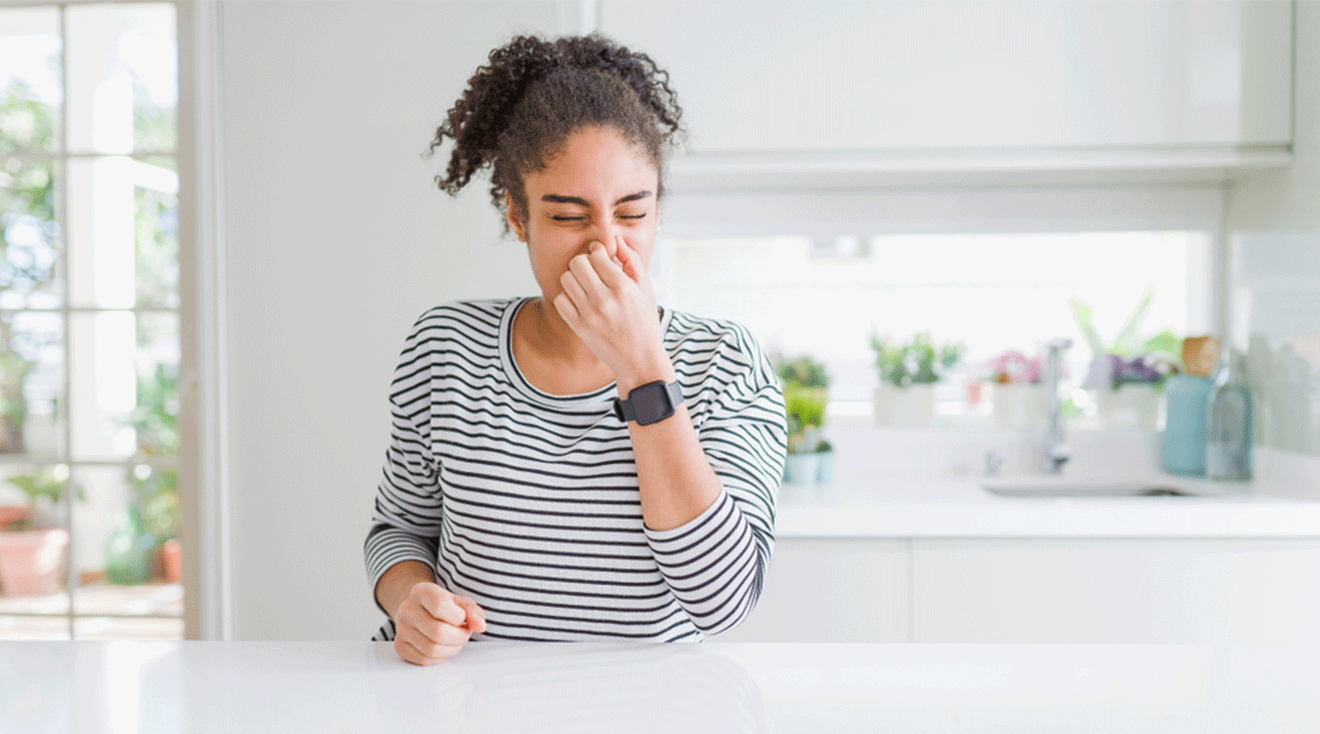 woman smelling something bad at home