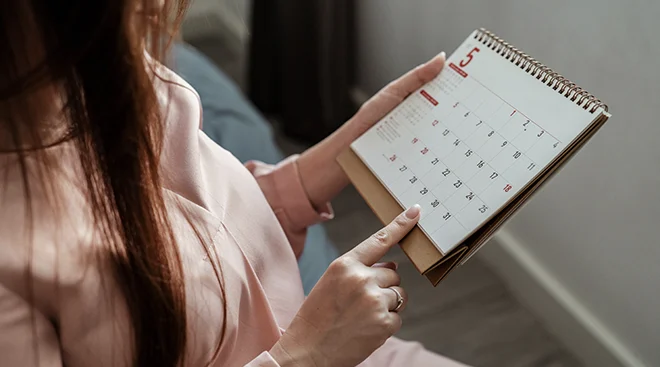 woman looking at a calendar in bedroom