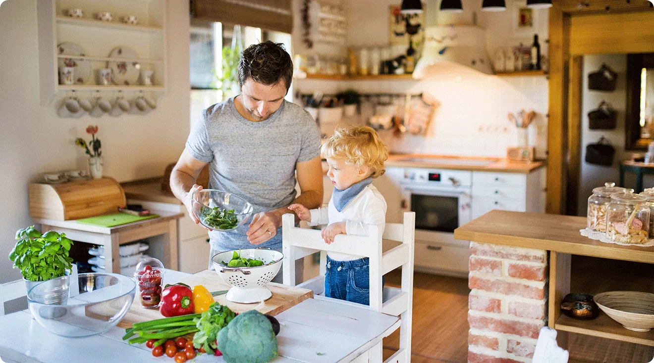 toddler using toddler tower while helping dad cook in kitchen