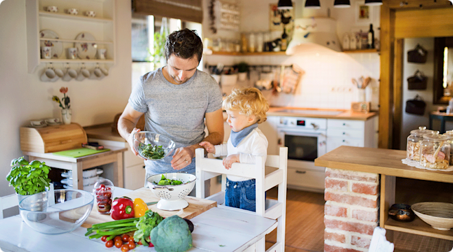 toddler using toddler tower while helping dad cook in kitchen