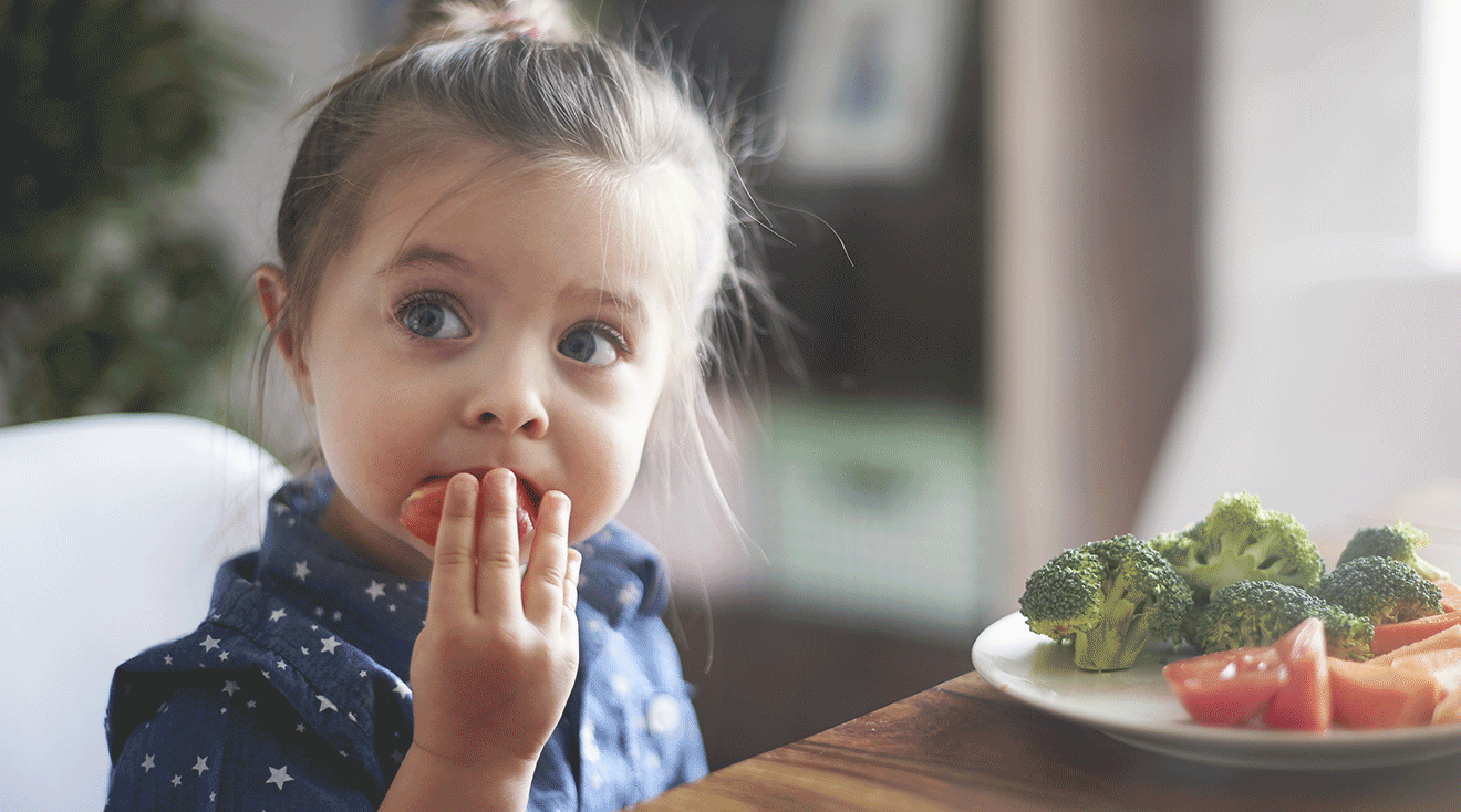 young girl eating vegetables