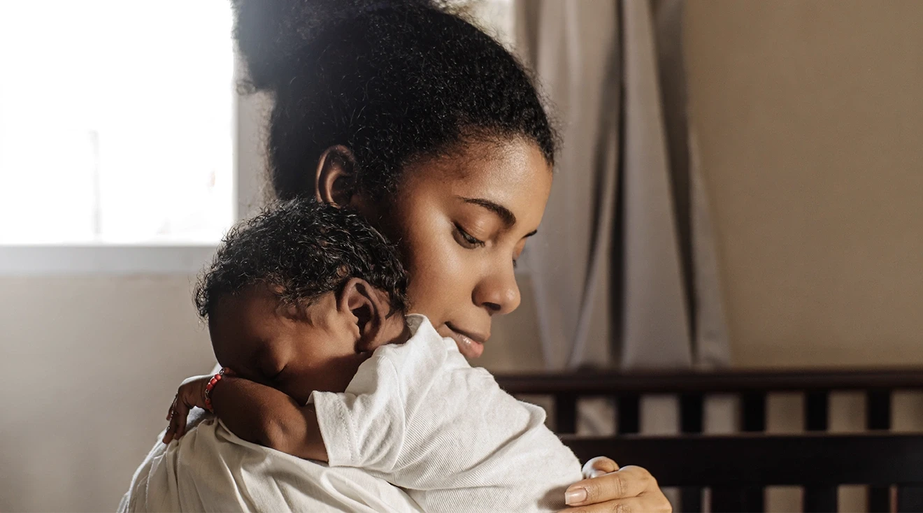 black mother holding newborn baby at home