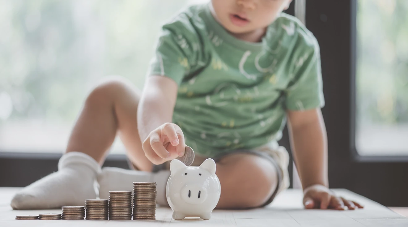 toddler putting money into piggy bank