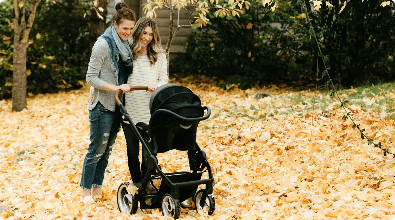 two moms pushing stroller outside during autumn