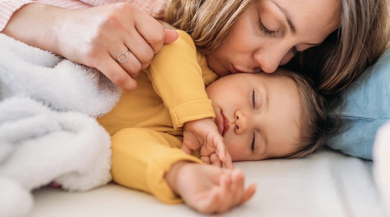 mother kissing sleeping baby