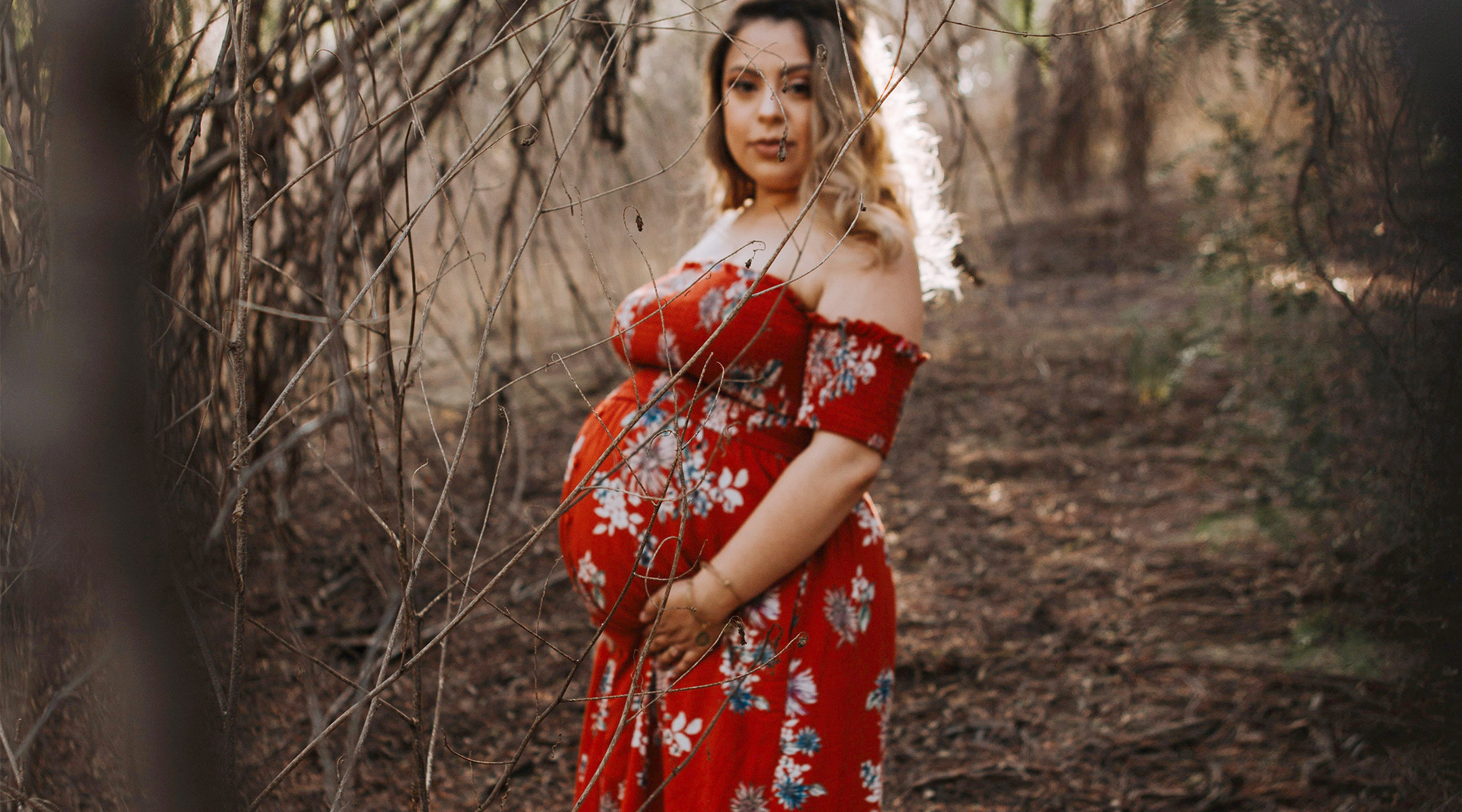 pregnant woman in nature backdrop wearing long floral dress
