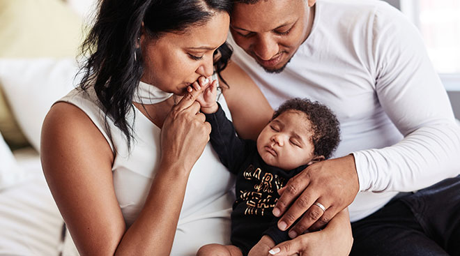 black parents kissing their newborn baby's hand