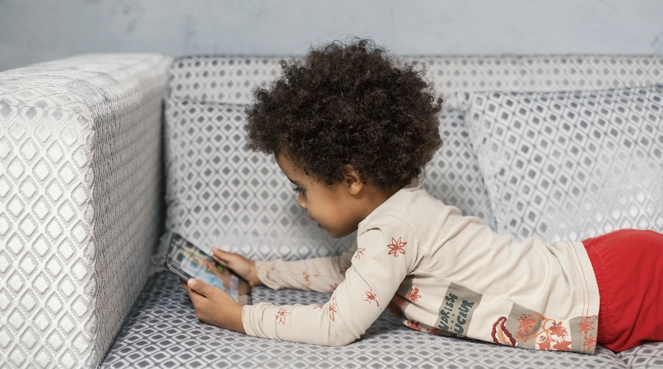 toddler using tablet on couch at home