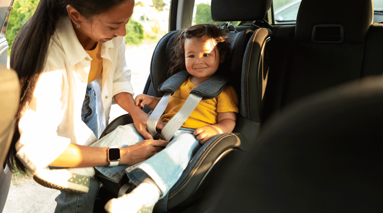 mom fastening toddler into car seat