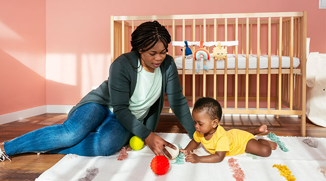 Mom playing with her young baby on the floor in his nursery. 