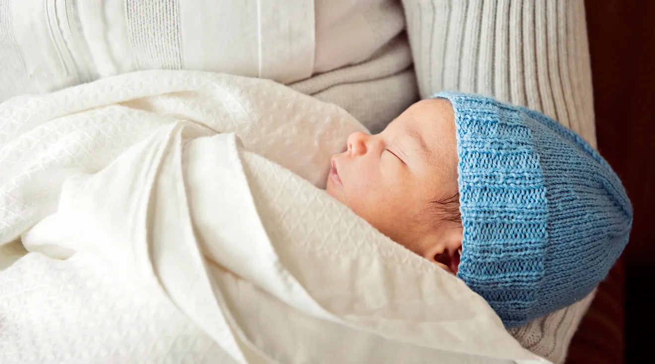 mother holding baby boy wearing blue hat