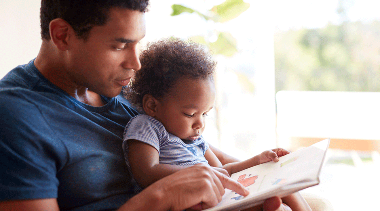 dad reading book with toddler at home