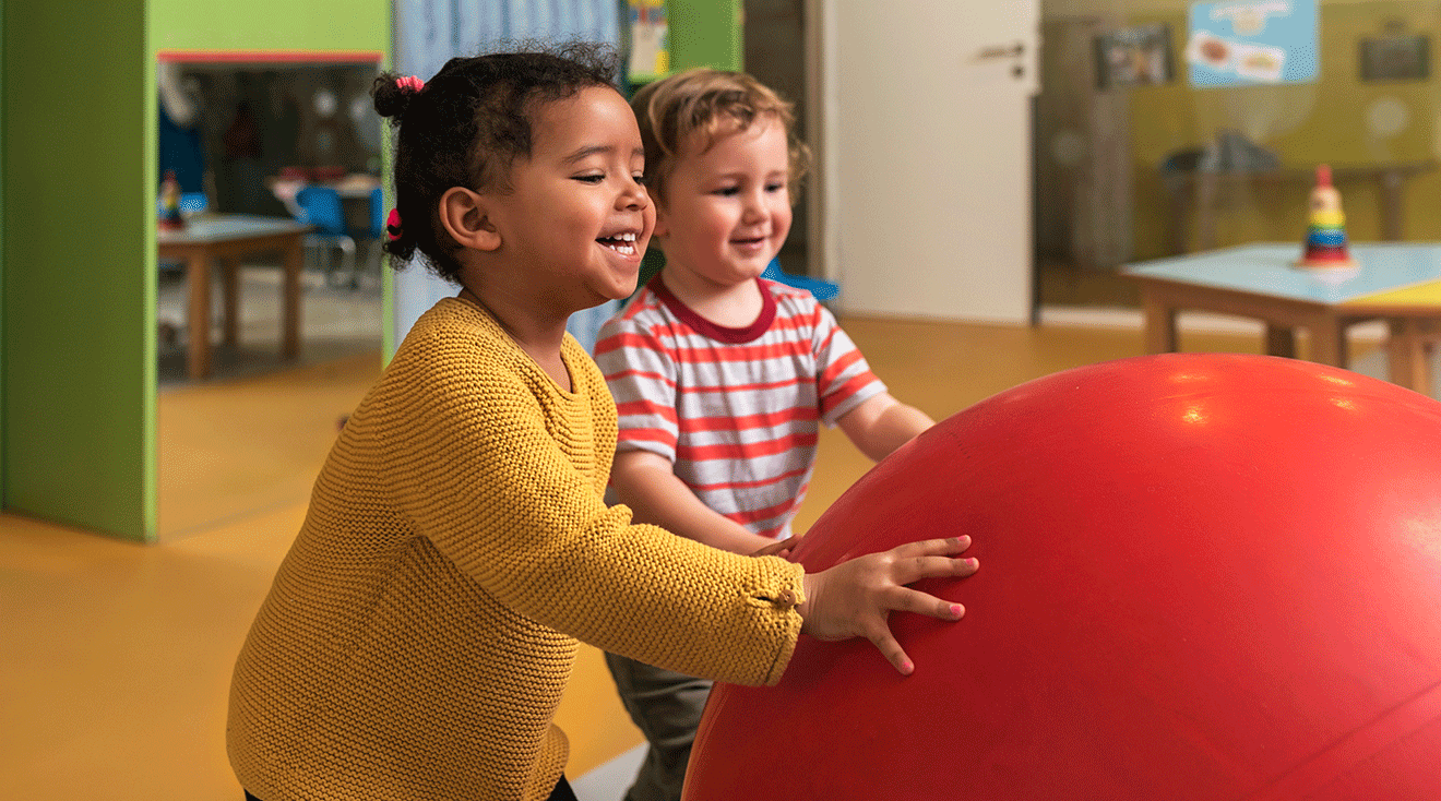 two toddlers playing with a ball at preschool 