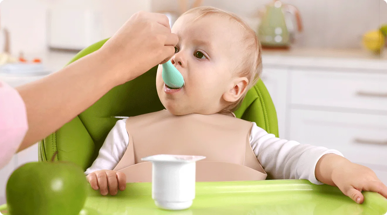 mom feeding yogurt to baby in high chair