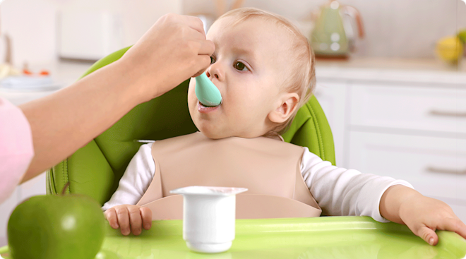 mom feeding yogurt to baby in high chair