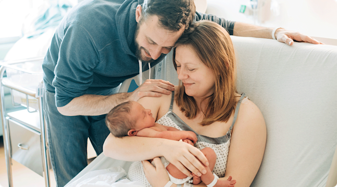 A mother and father with their newborn baby in the hospital.