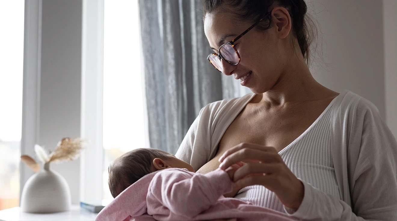 smiling mother breastfeeding baby at home