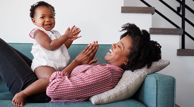 baby and mom clapping and smiling on couch together at home