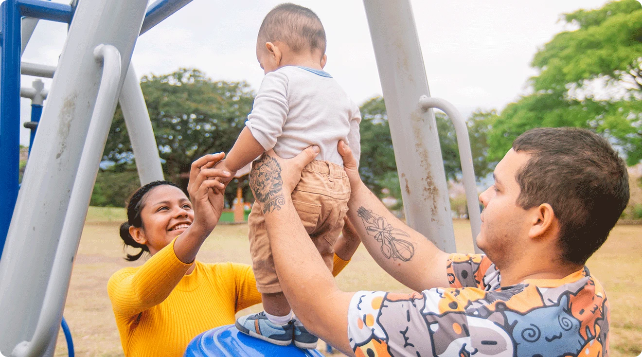 mom and dad playing with baby at the playground