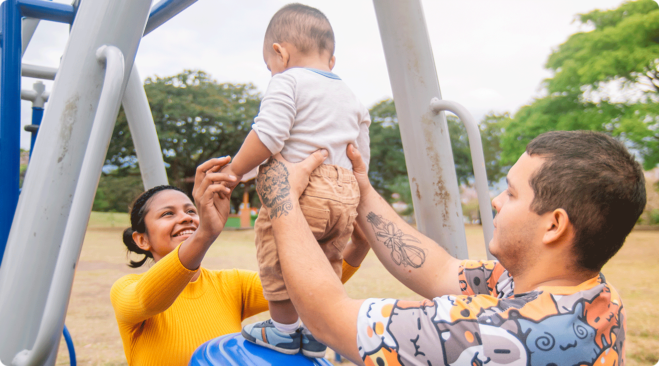 mom and dad playing with baby at the playground