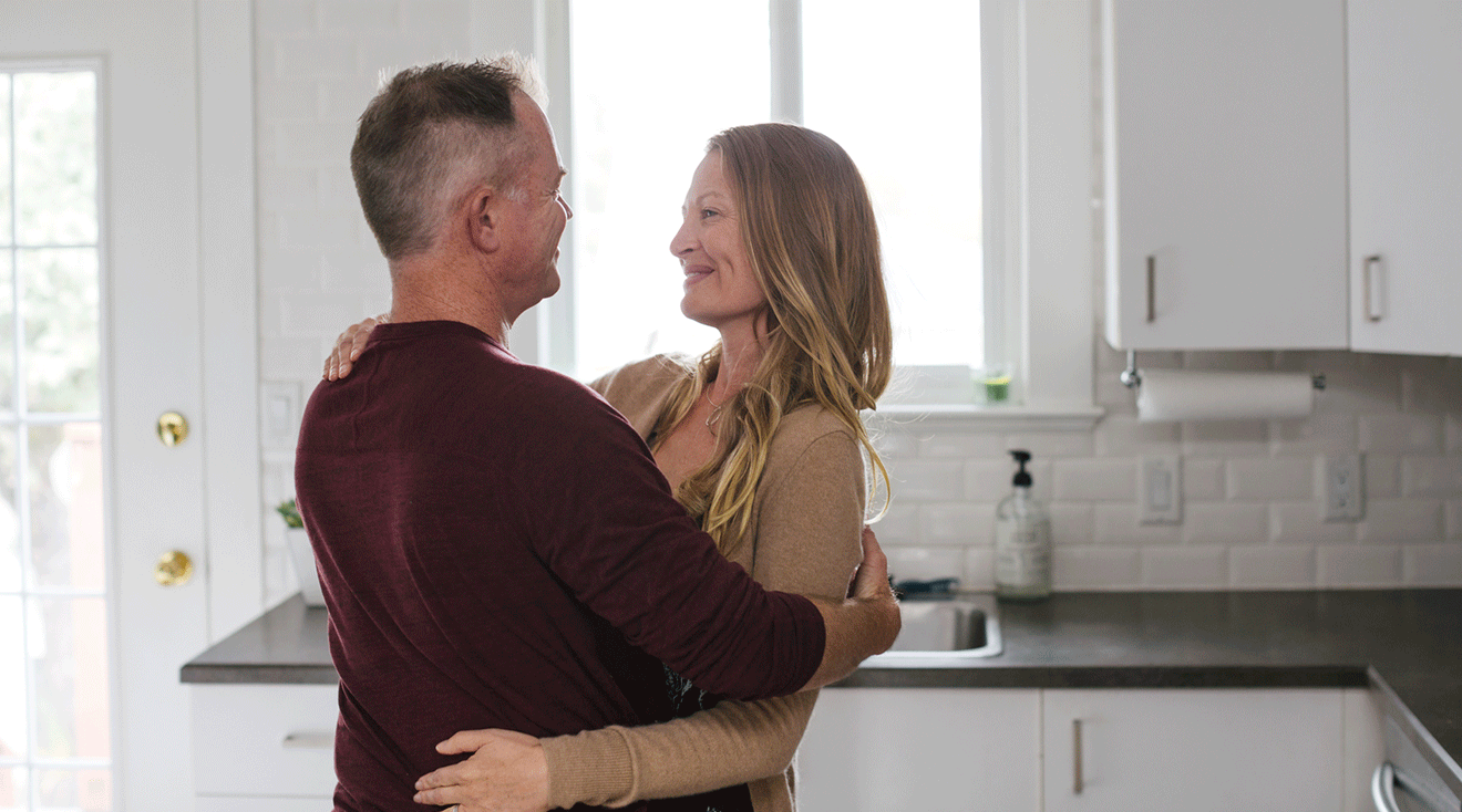 middle aged couple embracing in kitchen at home