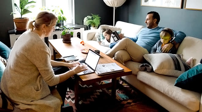 family with young children looking at their digital devices at home on the couch