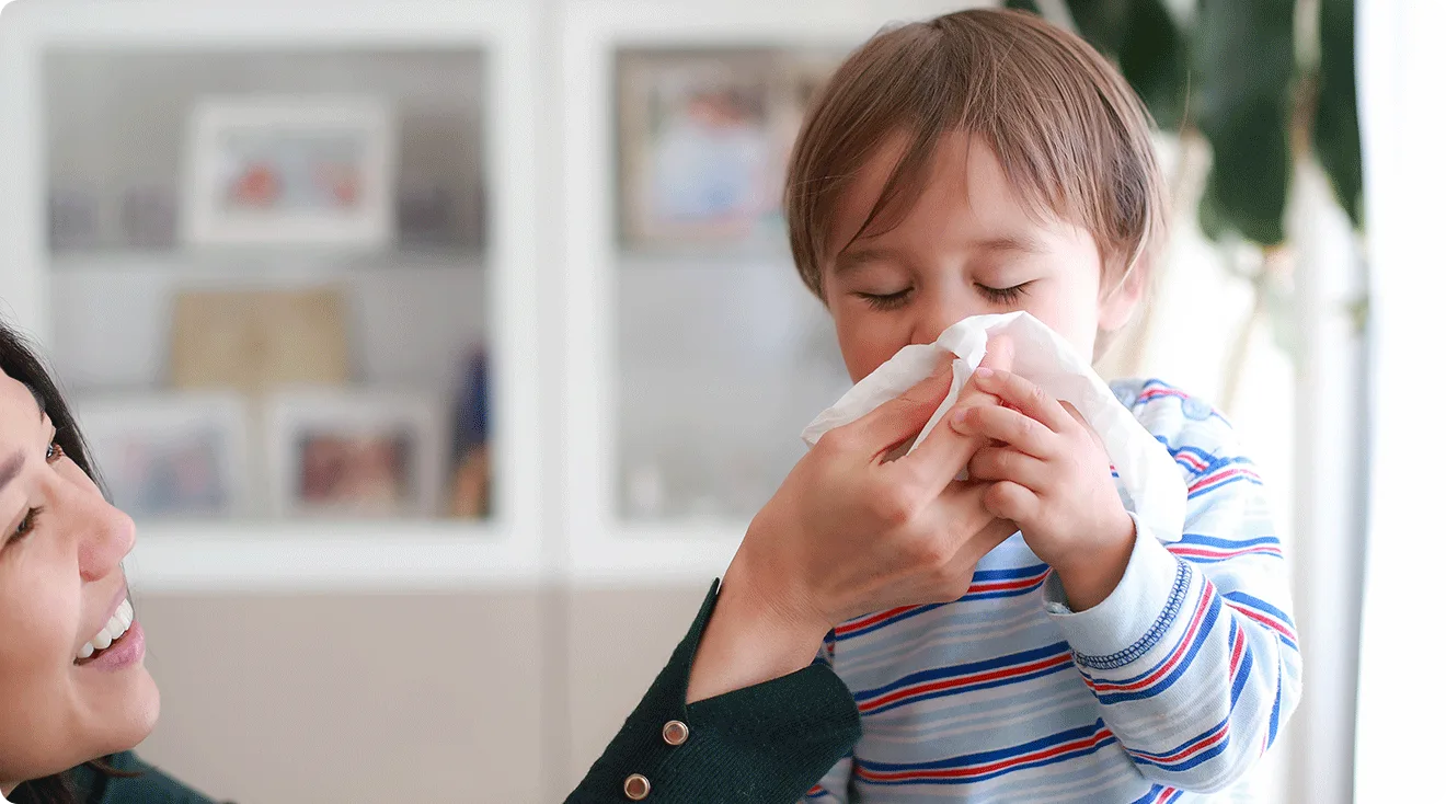 mom helping baby blow nose into tissue