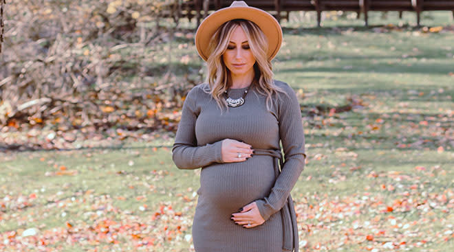 fashionable pregnant woman in outside setting wearing a hat