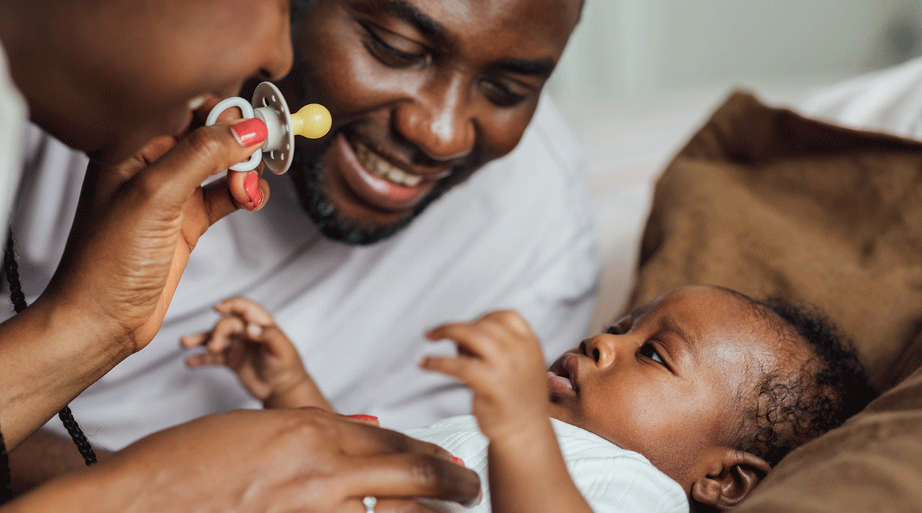 mom and dad giving pacifier to baby