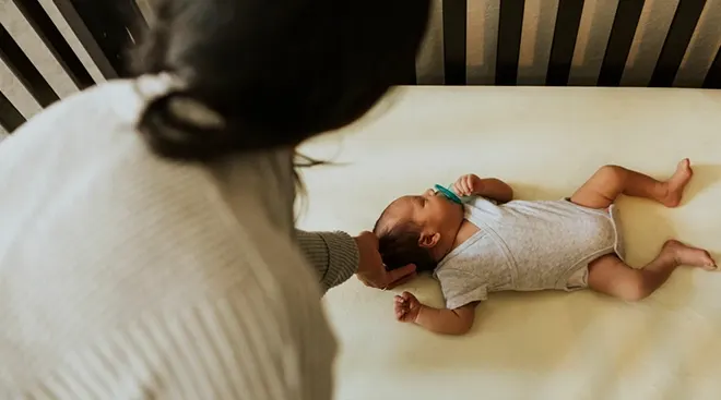 mother looking over baby sleeping in crib