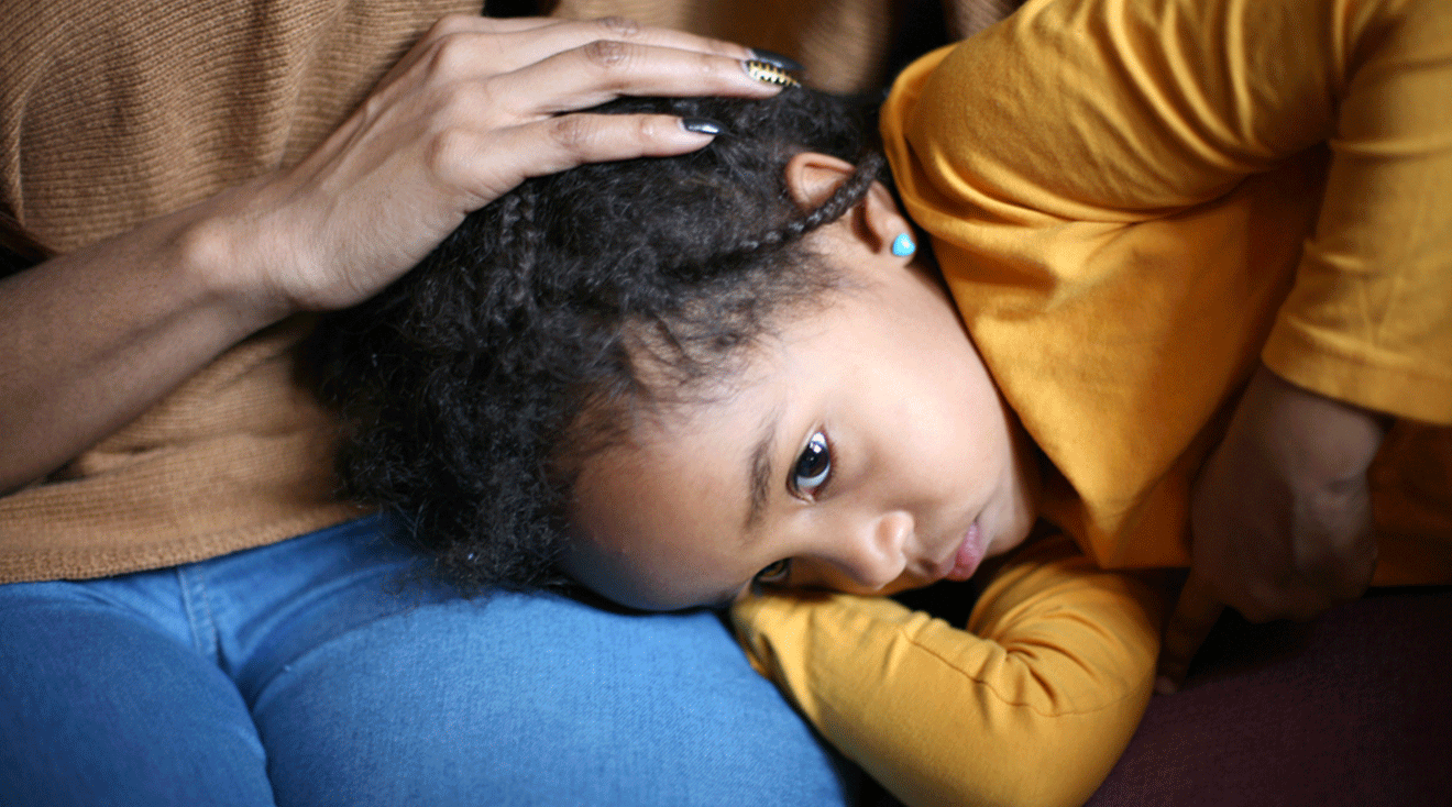 sick little girl laying with mom on the couch at home