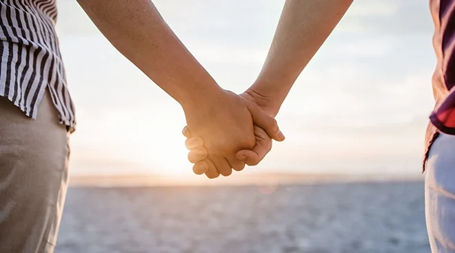 LGBTQ couple holding hands on the beach
