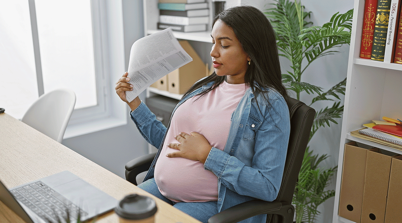 pregnant woman experiencing a hot flash while working at desk
