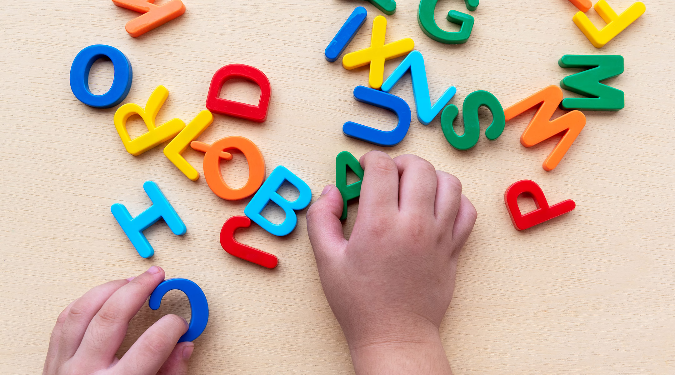 toddler hands playing with alphabet letters