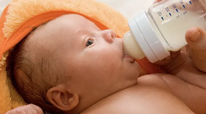 close up of baby drinking from bottle
