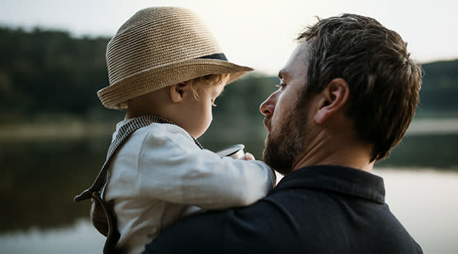 father holding toddler son during sunset outside