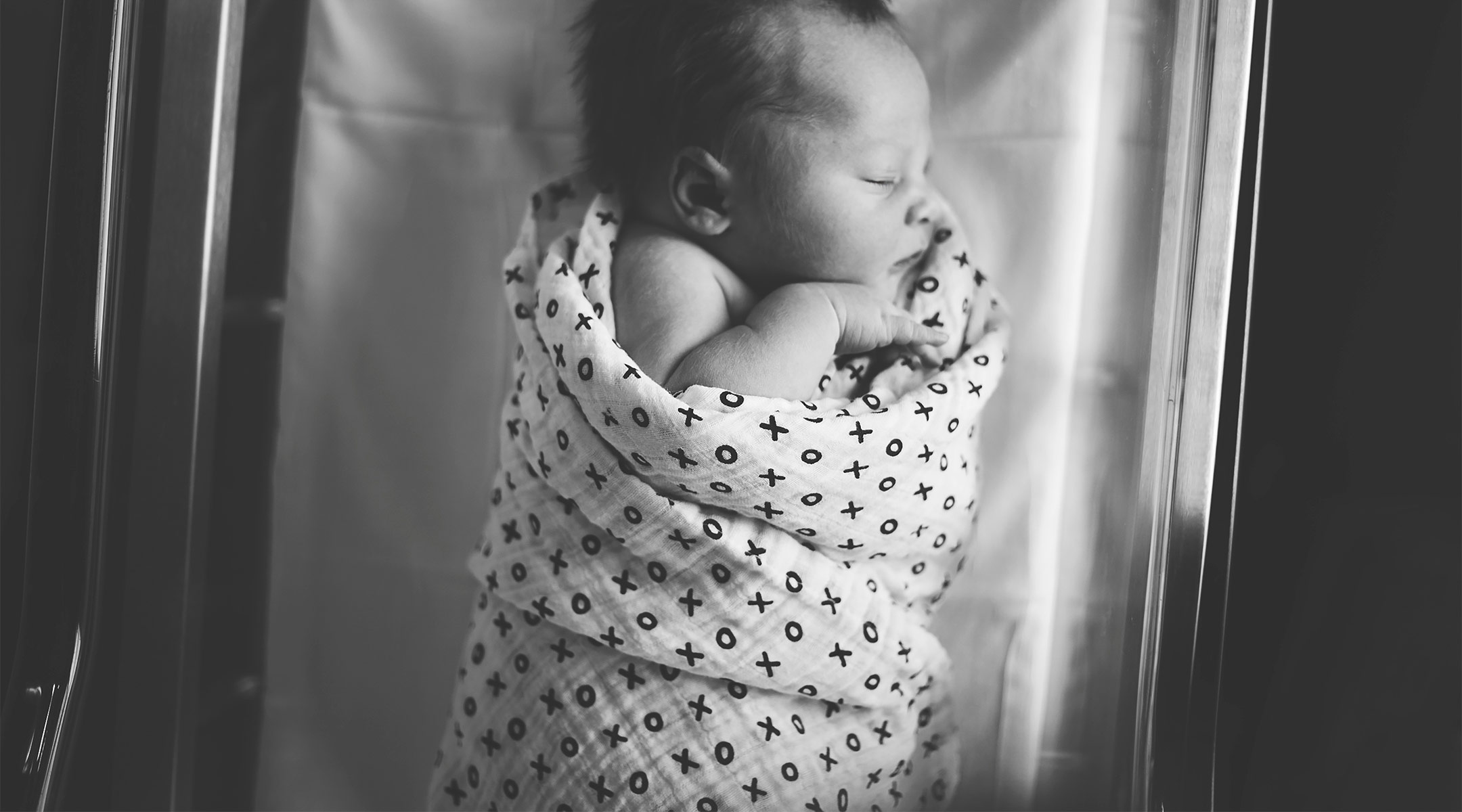 newborn baby wrapped in pattern blanket at the hospital