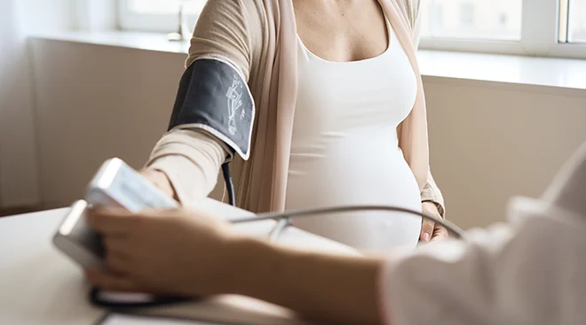 pregnant woman getting blood pressure measured by doctor