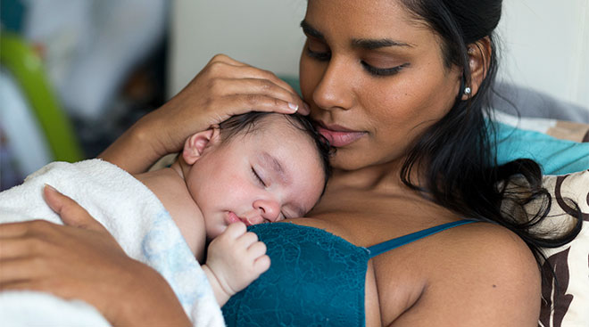 Mom holds baby on her chest after breastfeeding. 