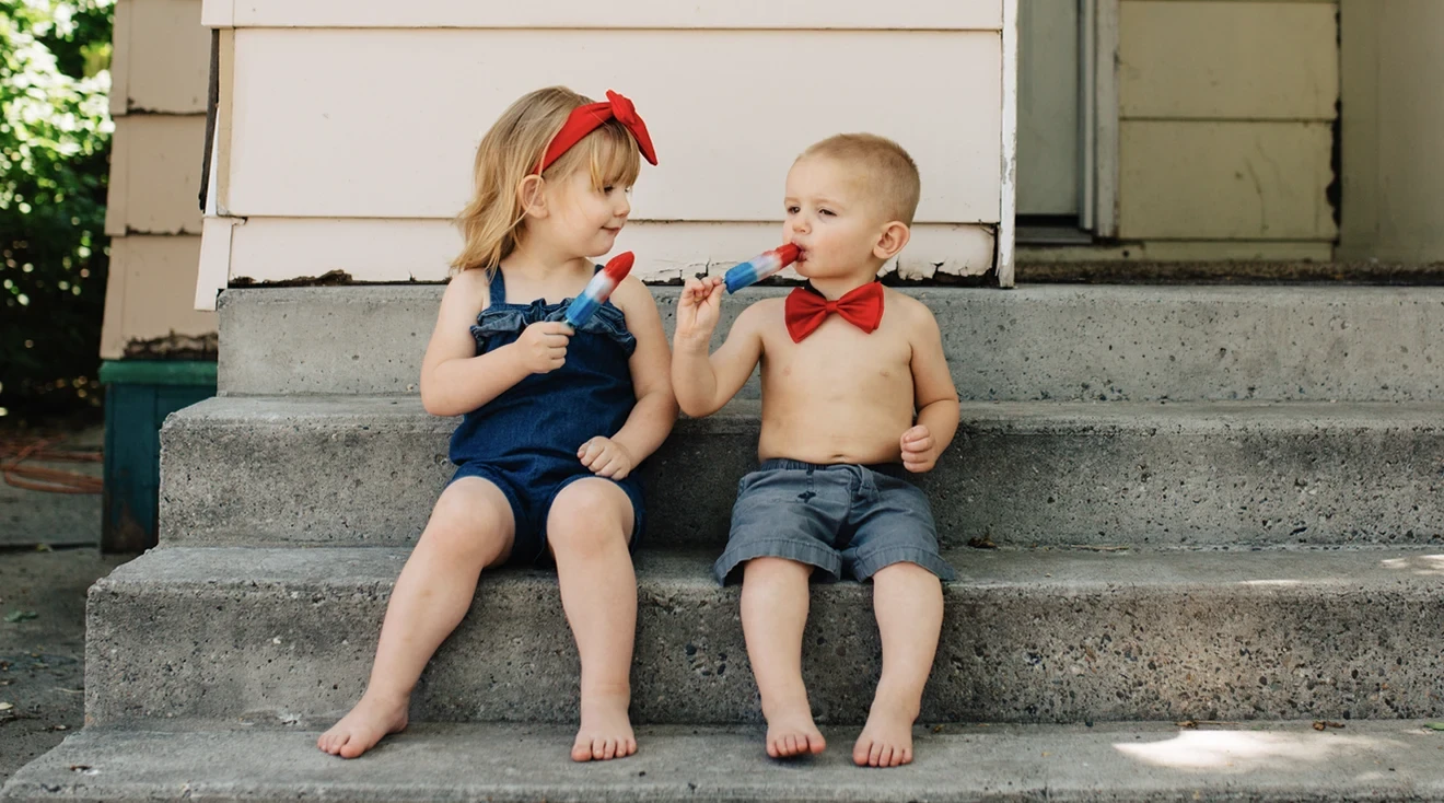 two small children enjoying popsicles outside in the summer
