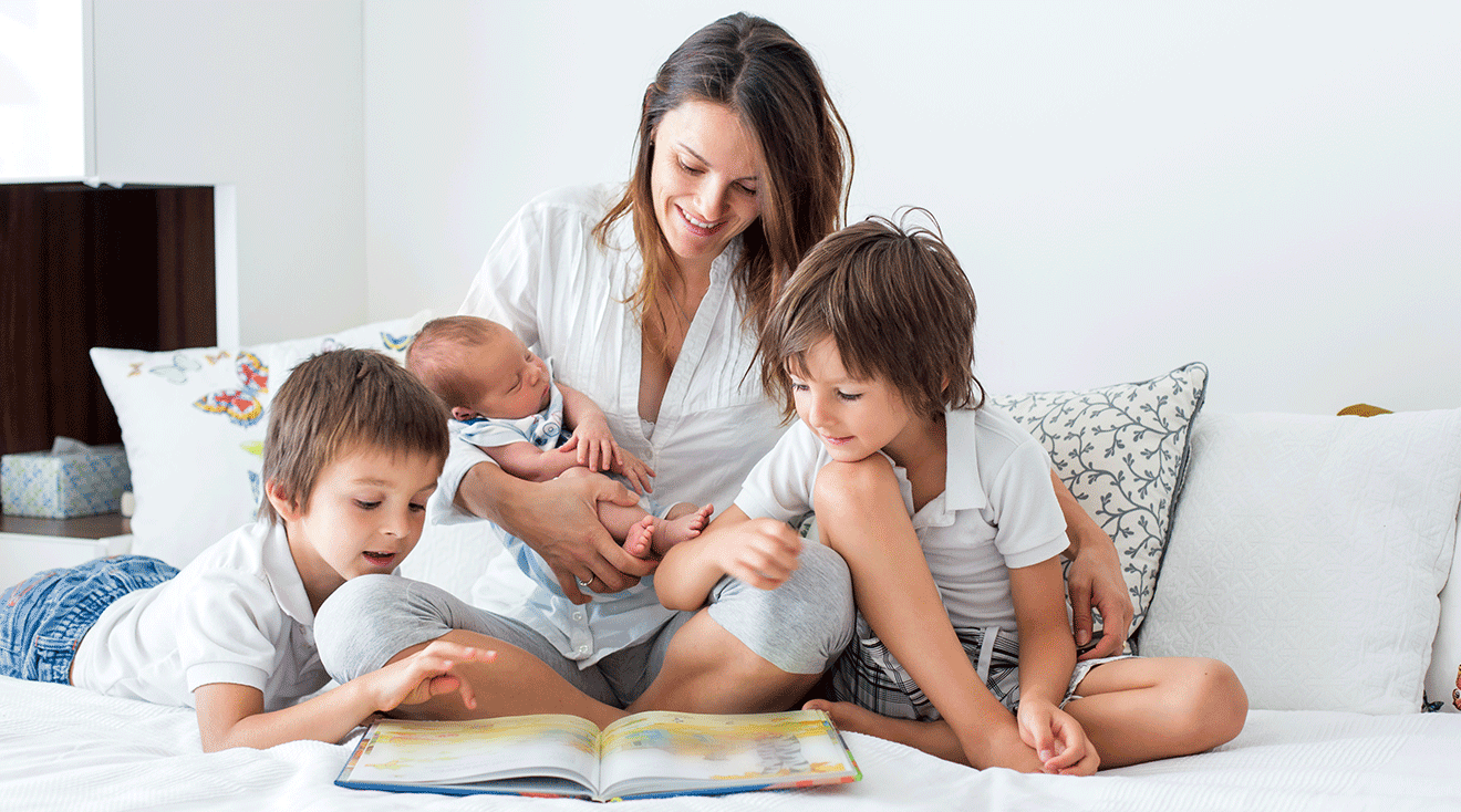 mother reading a book with 3 children at home