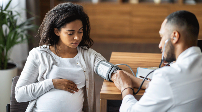 doctor checking pregnant woman's blood pressure