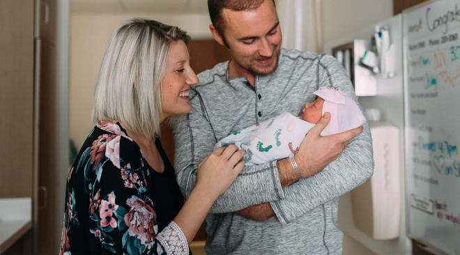 new parents holding their newborn baby in the hospital