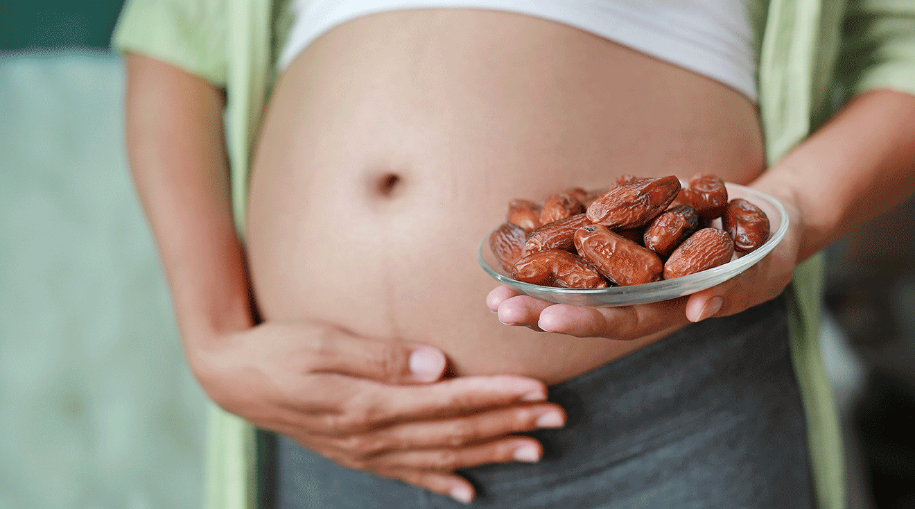 pregnant woman holding a bowl of dates