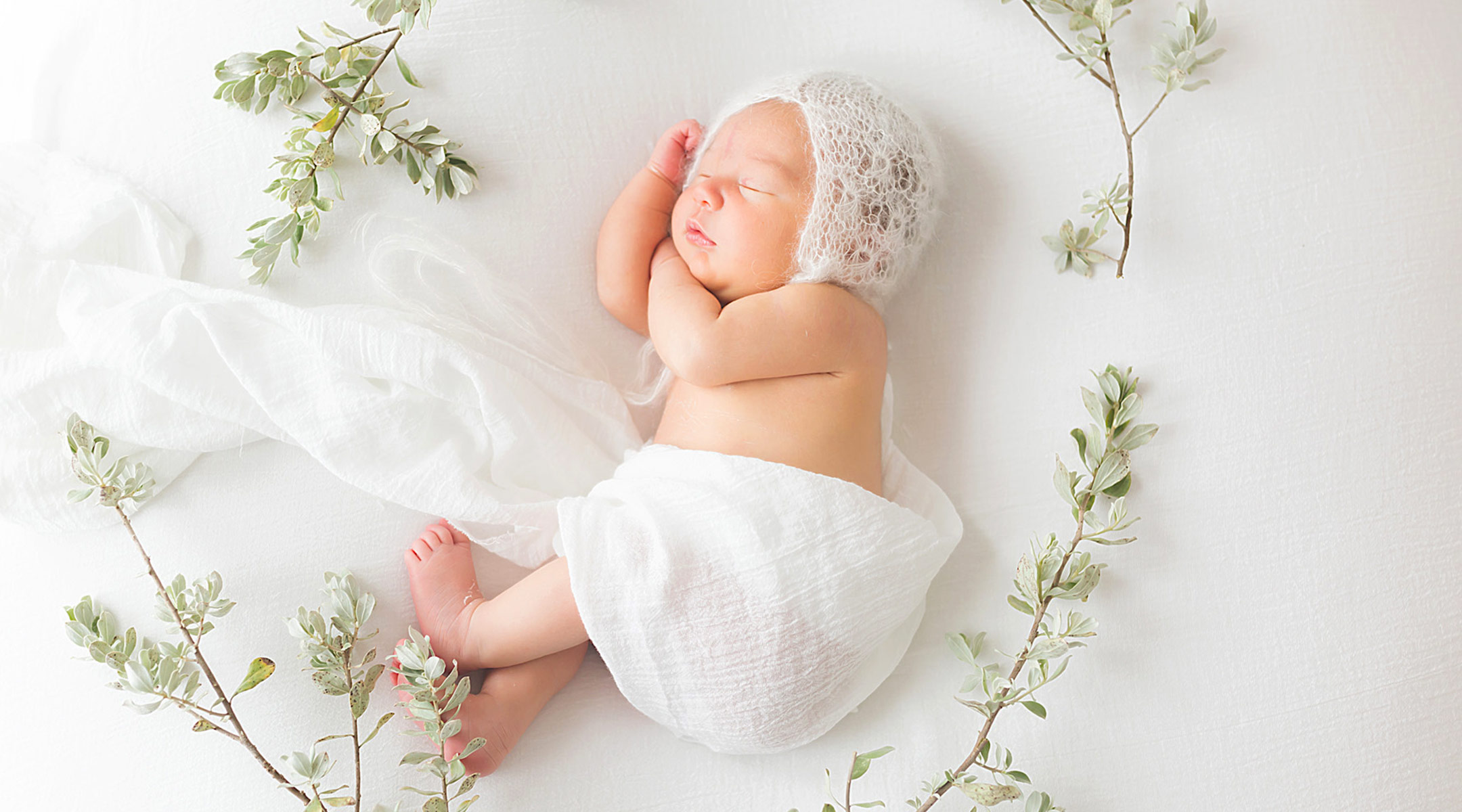 baby sleeping and wearing a white knit bonnet