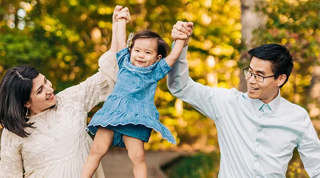 mom and dad both lifting up their toddler 